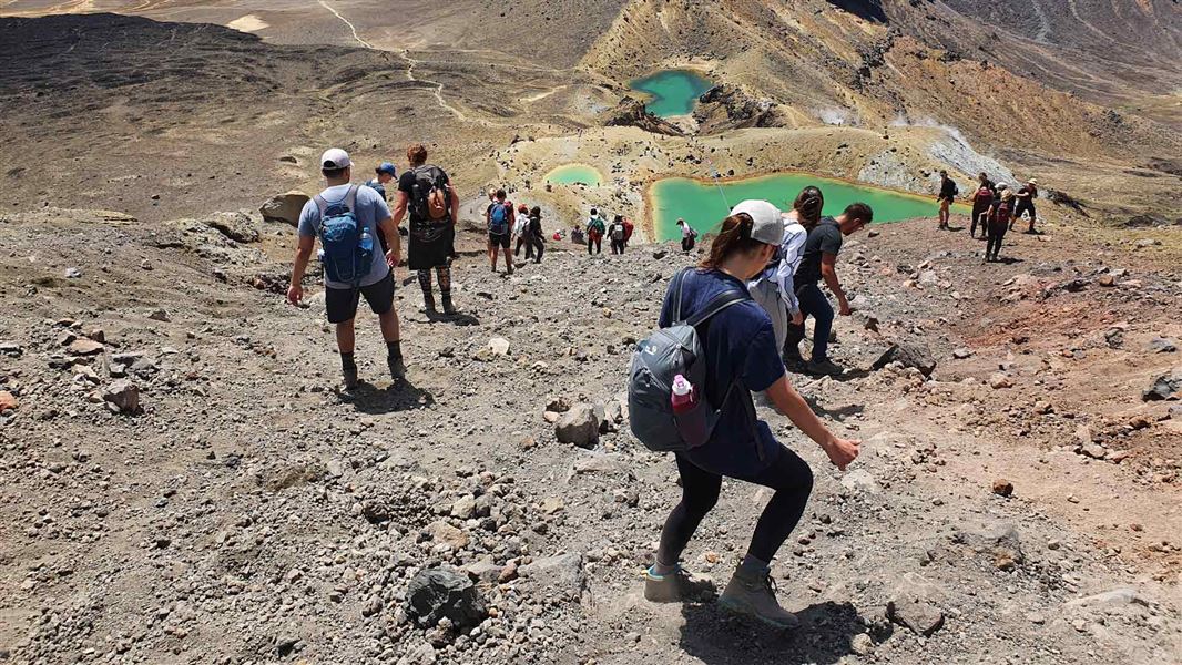 A group of people making their way carefully down a loose rocky hill.